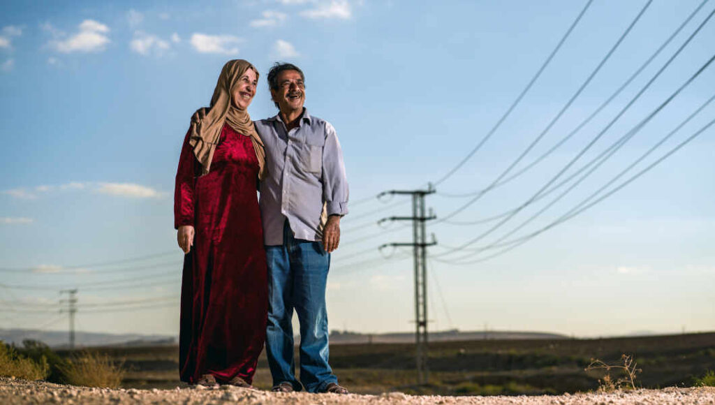Abu Munir and his wife stand on a ridge outside their home.
