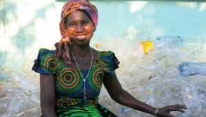 Benita Chikaluma sits with her bottles, demonstrating an important part of the definition of microcredit