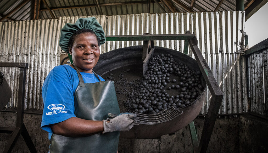 Sanivation employee in front of charcoal briquettes.
