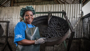 Sanivation employee in front of charcoal briquettes.