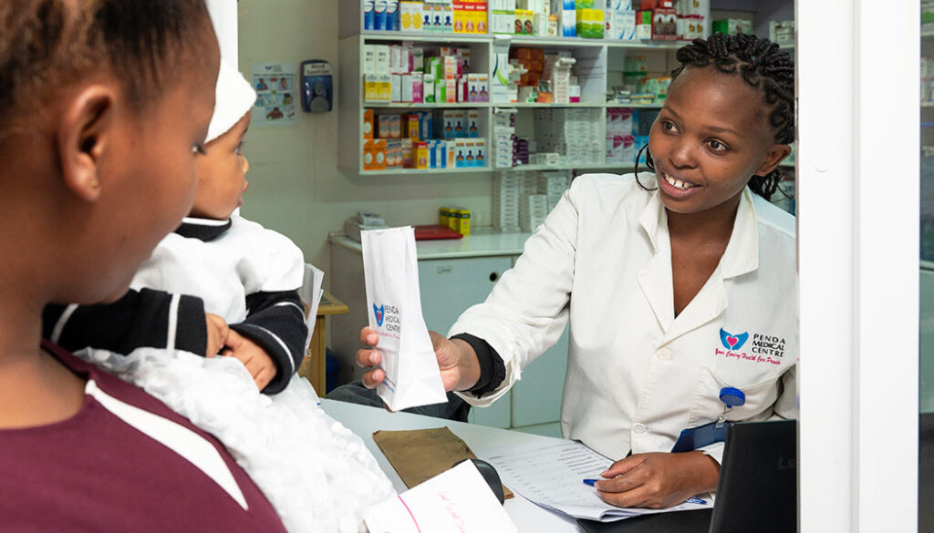 A Penda Health employee hands a customer their prescription