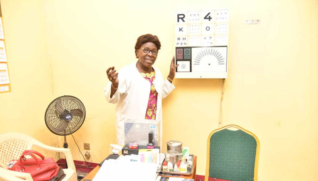 Rose Michelle displays the eye chart she uses to assess clients. As the COVID-19 pandemic winds down, Rose's business is coming back, a hopeful harbinger for Africa's economic outlook.