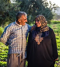 Homme et femme souriants se tenant ensemble dans un champ vert. Cliquez pour en savoir plus sur l'agriculture. 